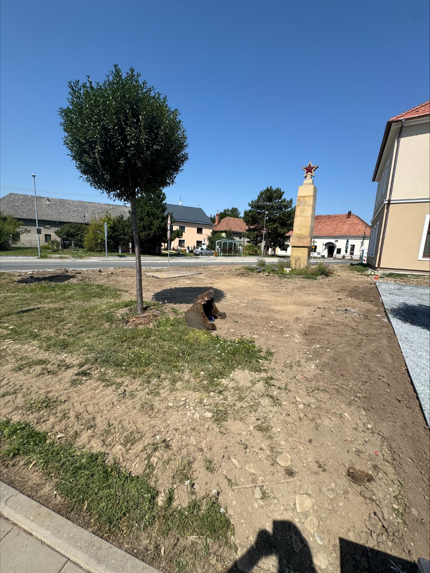 Nerovný, vyhrabaný terén v obci před úpravou