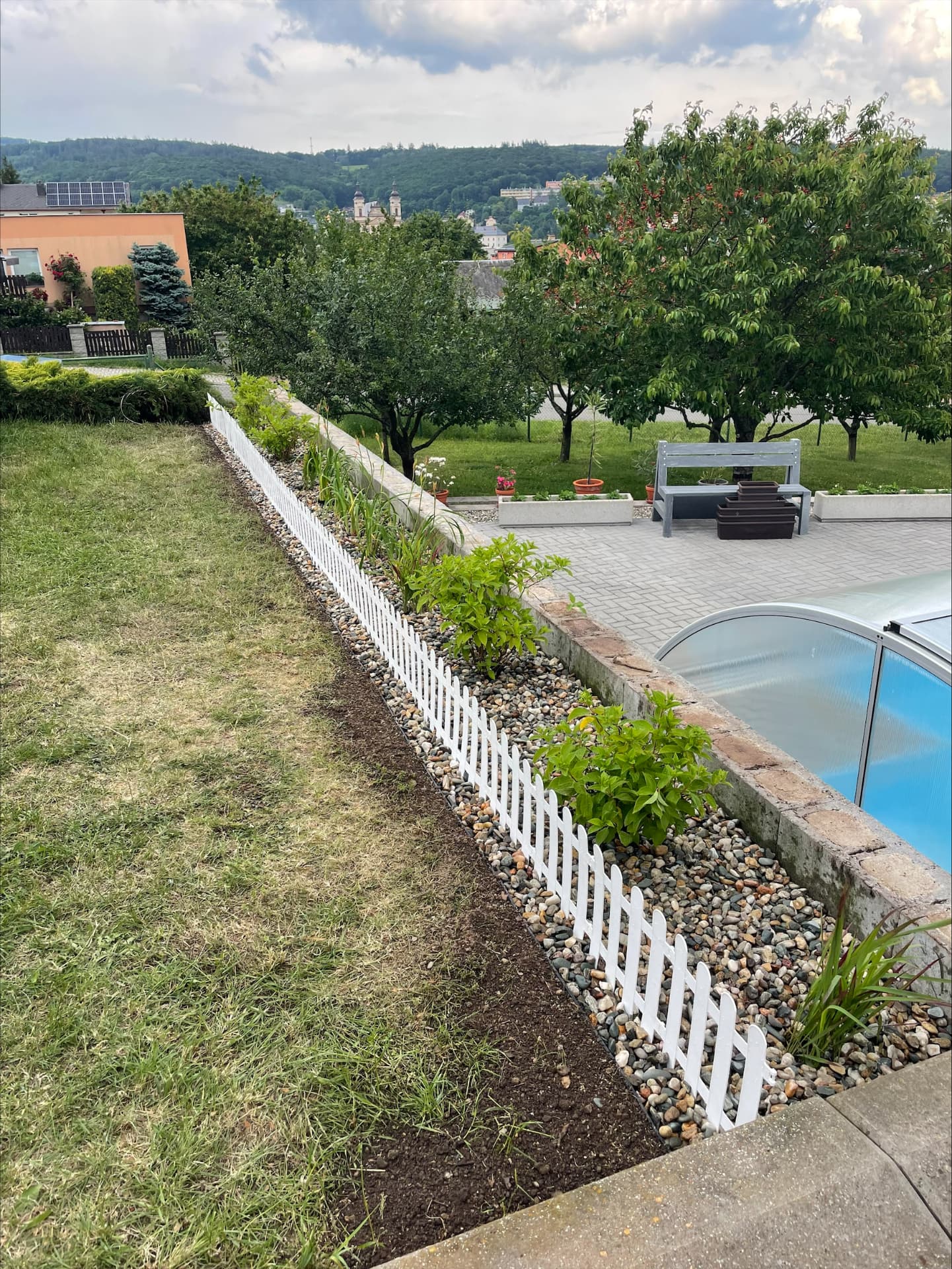 Upravená zahrada s bílou obrubou a záhonem po úpravě